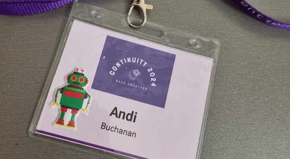 A badge with the Continuity logo, the name Andi Buchanan, and a green and red robot sticker